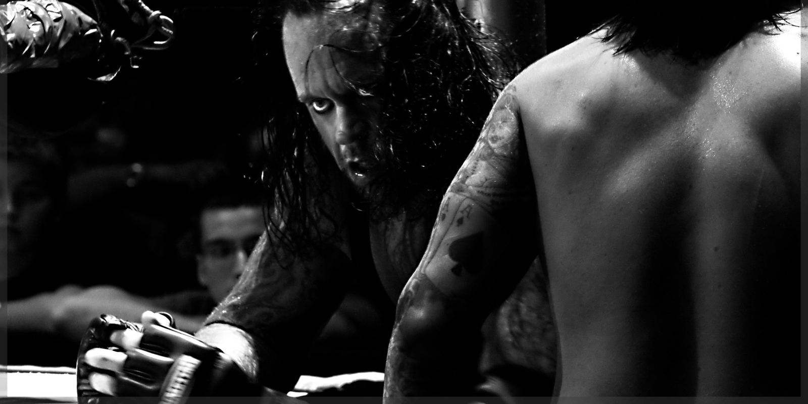 The Undertaker standing in the ring in a long black coat and hat